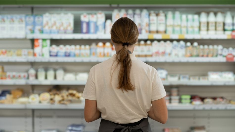 A women standing faceing a grocery isle.