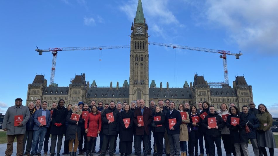 A group of people (Unifor leadership and staff) stand in front of Parliament Hill.