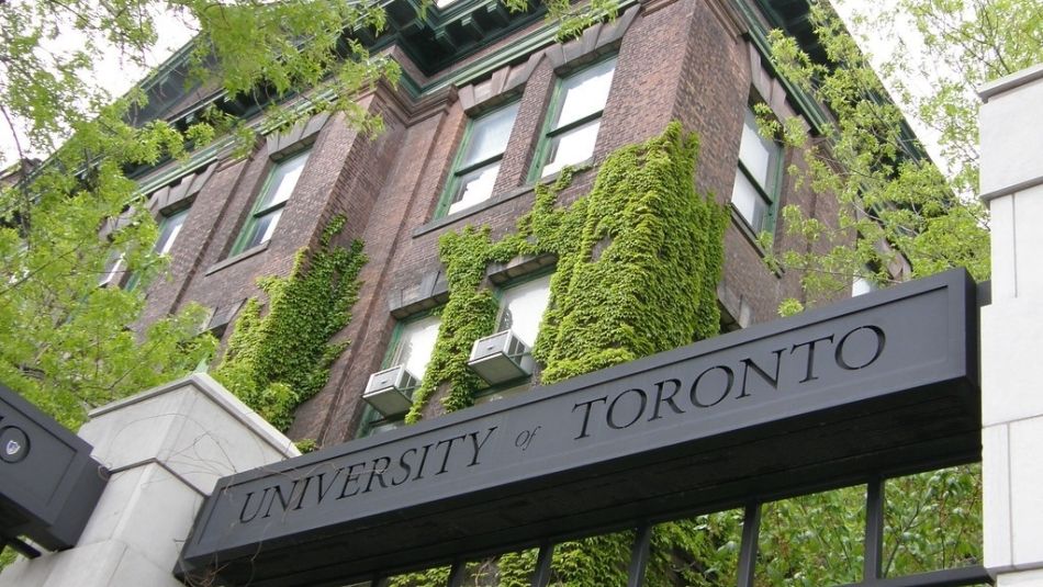 A University of Toronto sign with building and trees shot from below.
