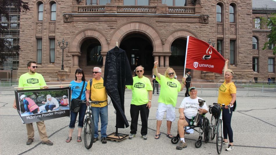 A handfull of activists in matching shirts rally in front of Queen's Park.