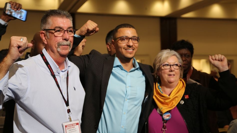 OFL President Chris Buckley, Secretary-Treasurer, Patty Coates and Executive Vice-President, Ahmad Gaied, raise their fists in solidarity.