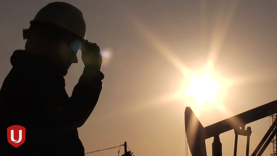 Side silhouette of a worker in a hardhat against a setting sun