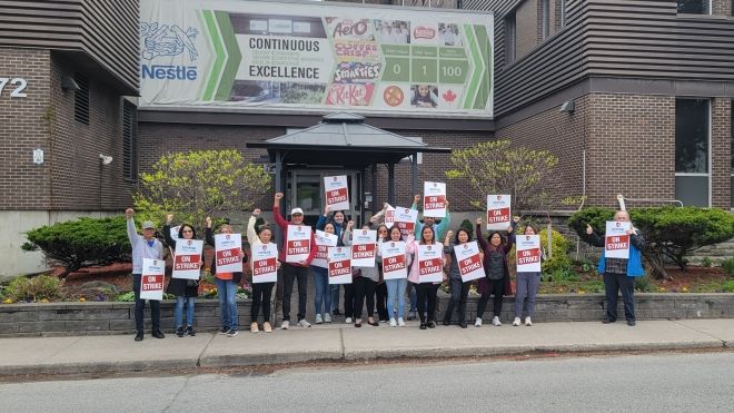 A group of people holding On Strike signs under the Nestle sign.