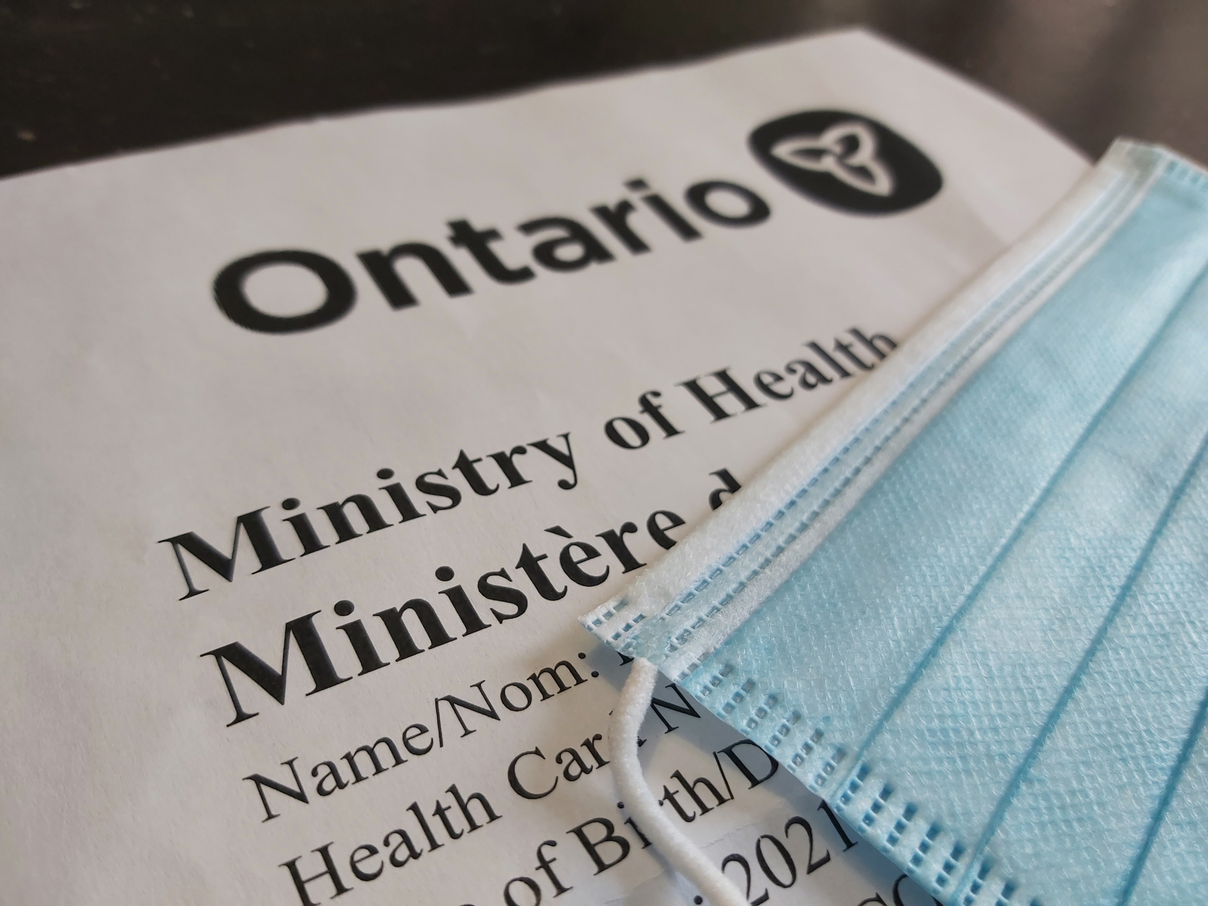 A blue mask covering a printed covid-19 vaccine reciept