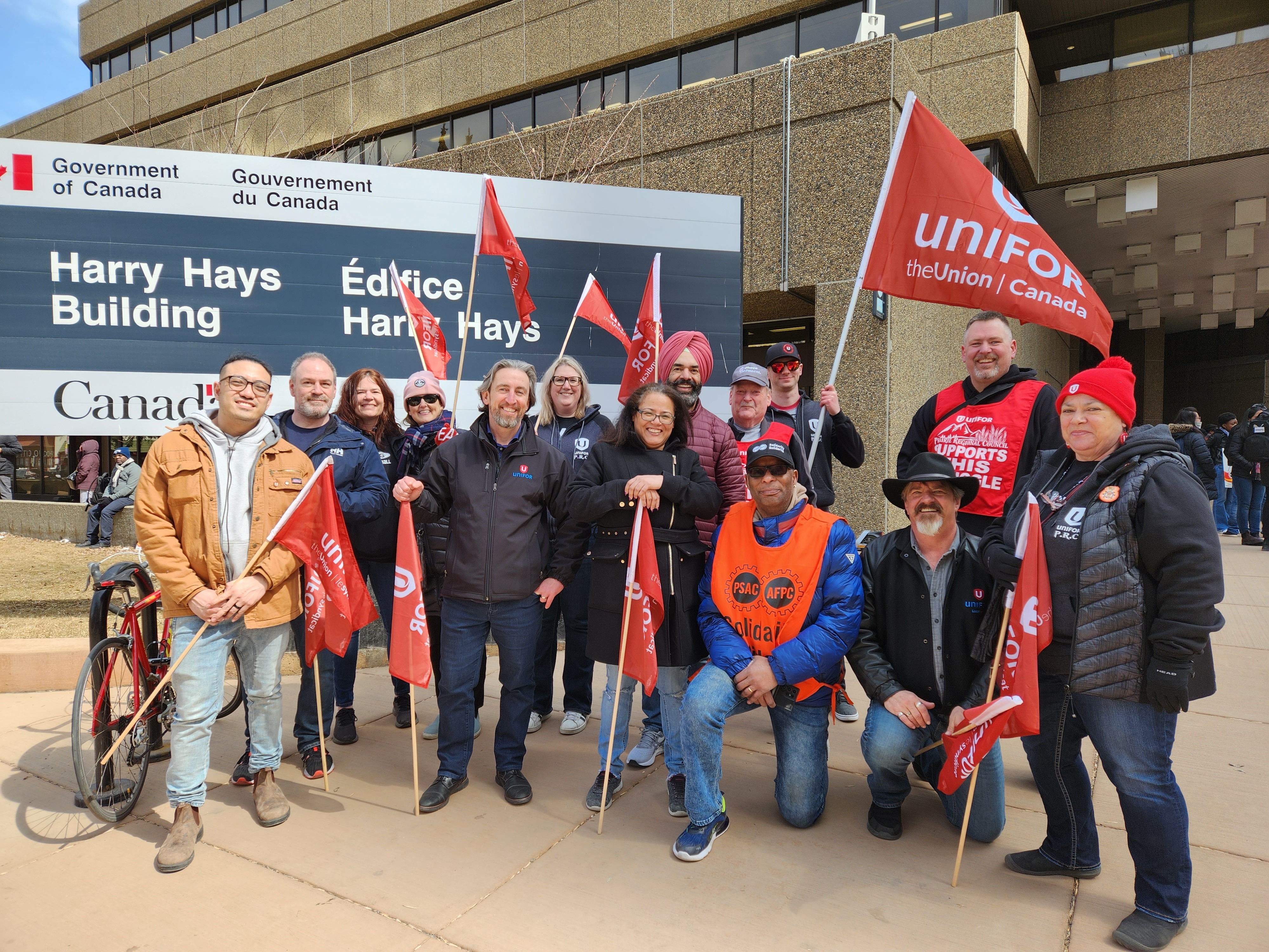 Les dirigeants d'Unifor et les membres de la Colombie-Britannique posant avec des drapeaux sur le piquet de grève de l'ACSP.