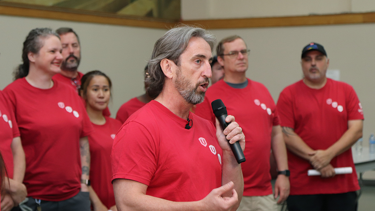 A man at a microphone with people standing behind him