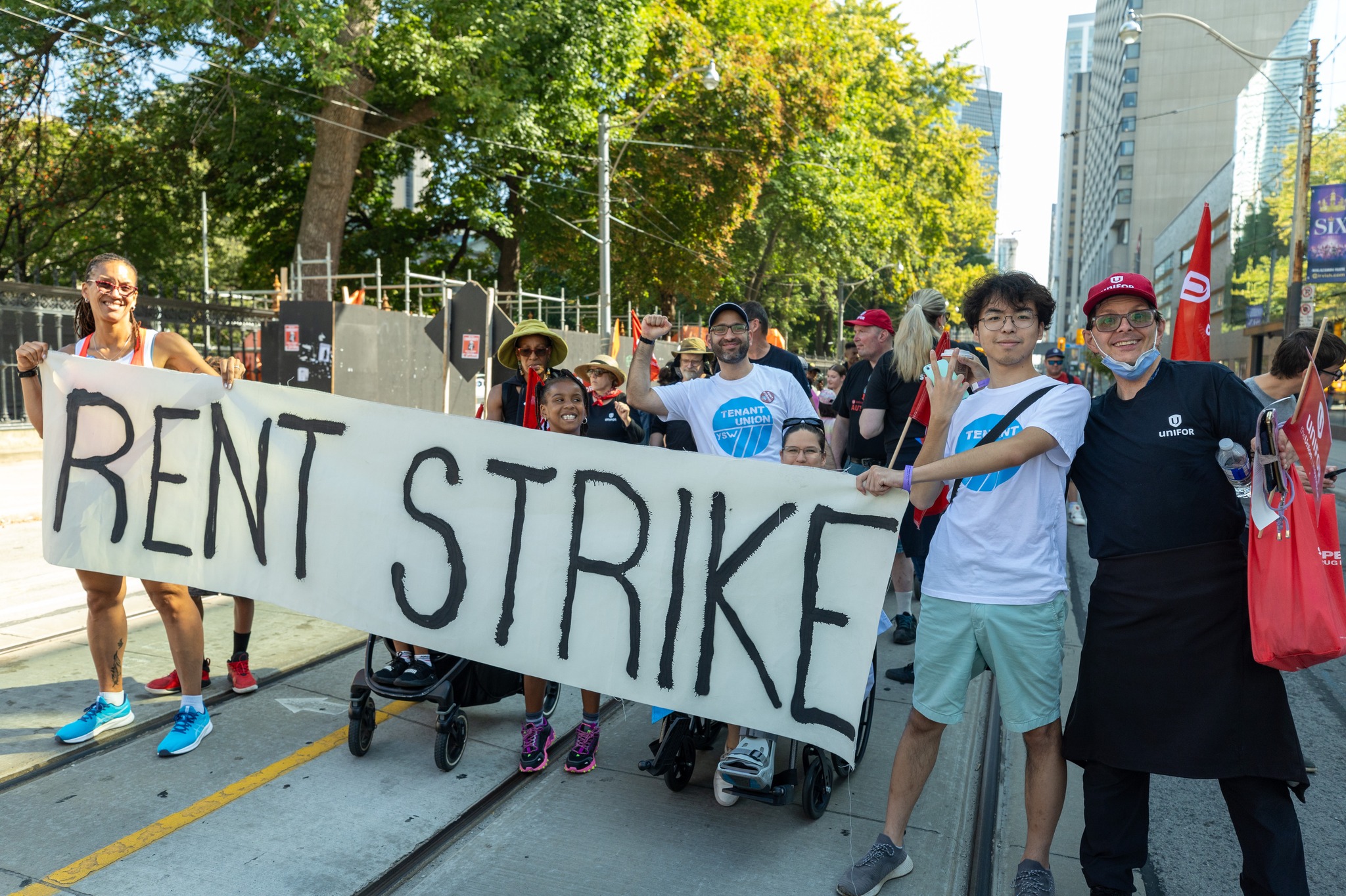 a parade of people marching holing a banner "Rent Strike"