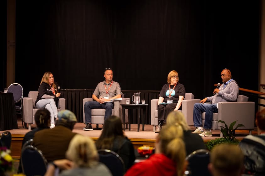 Four people sit on a pannel on stage