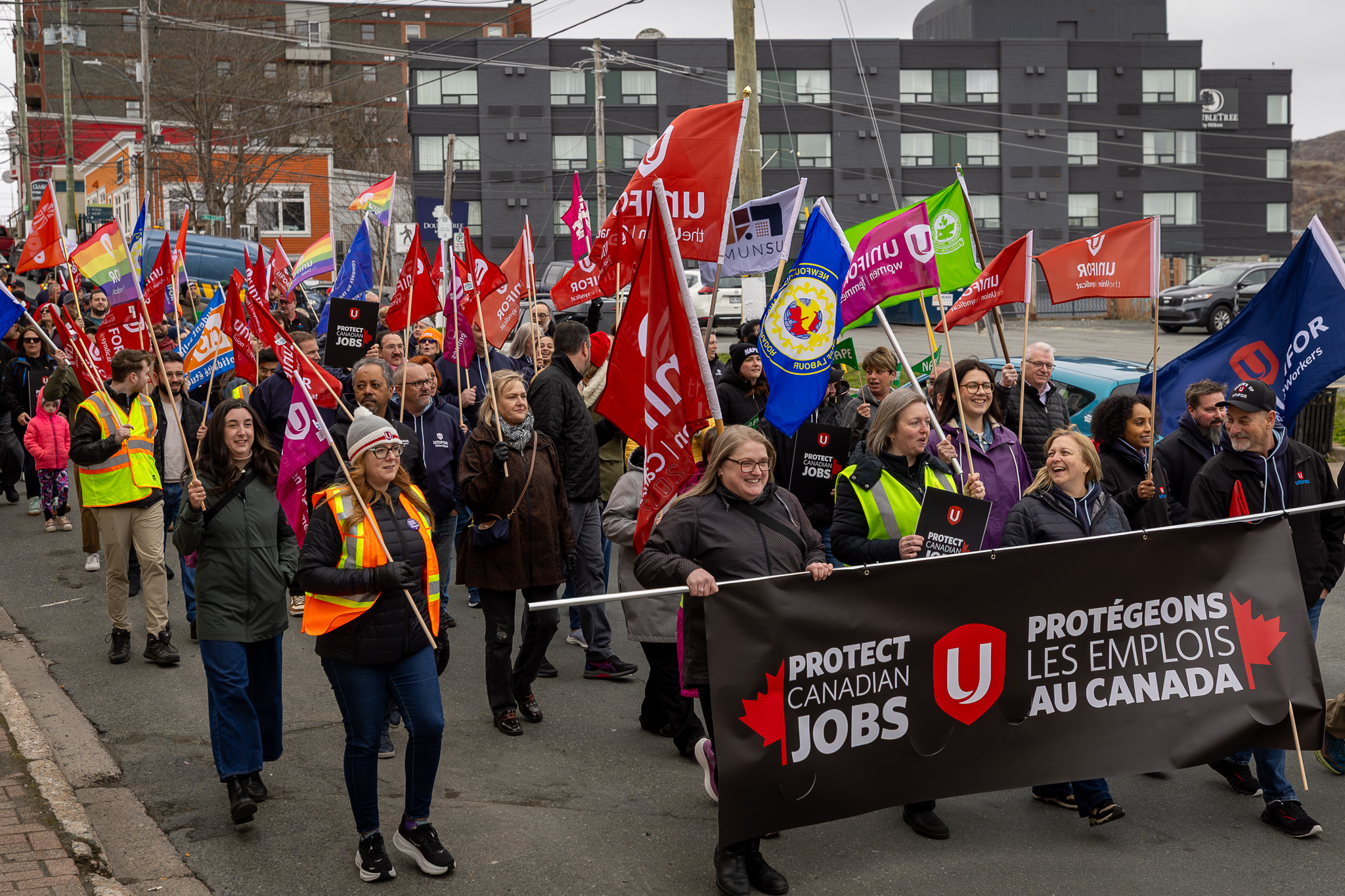 A large rally people walkin with banners and Unifor flags