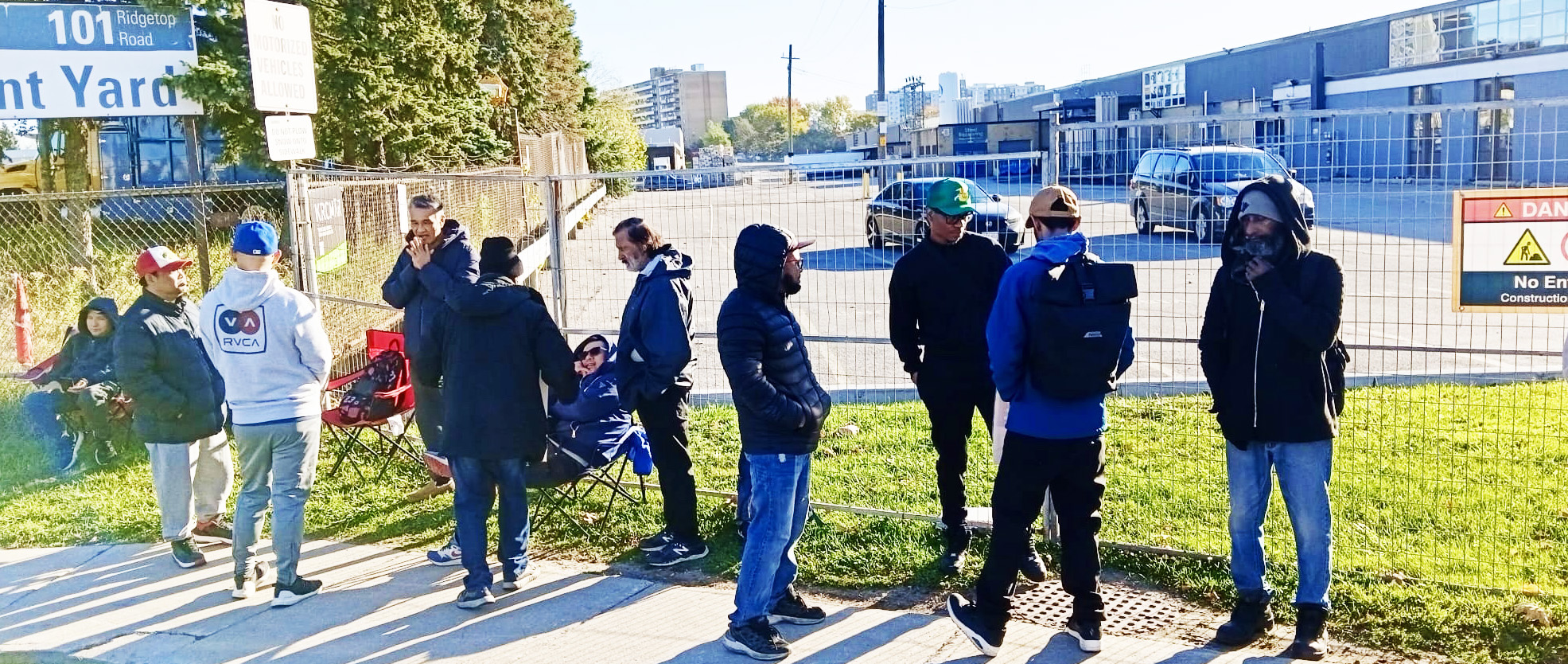 A group of picketers stand outside a wired fence