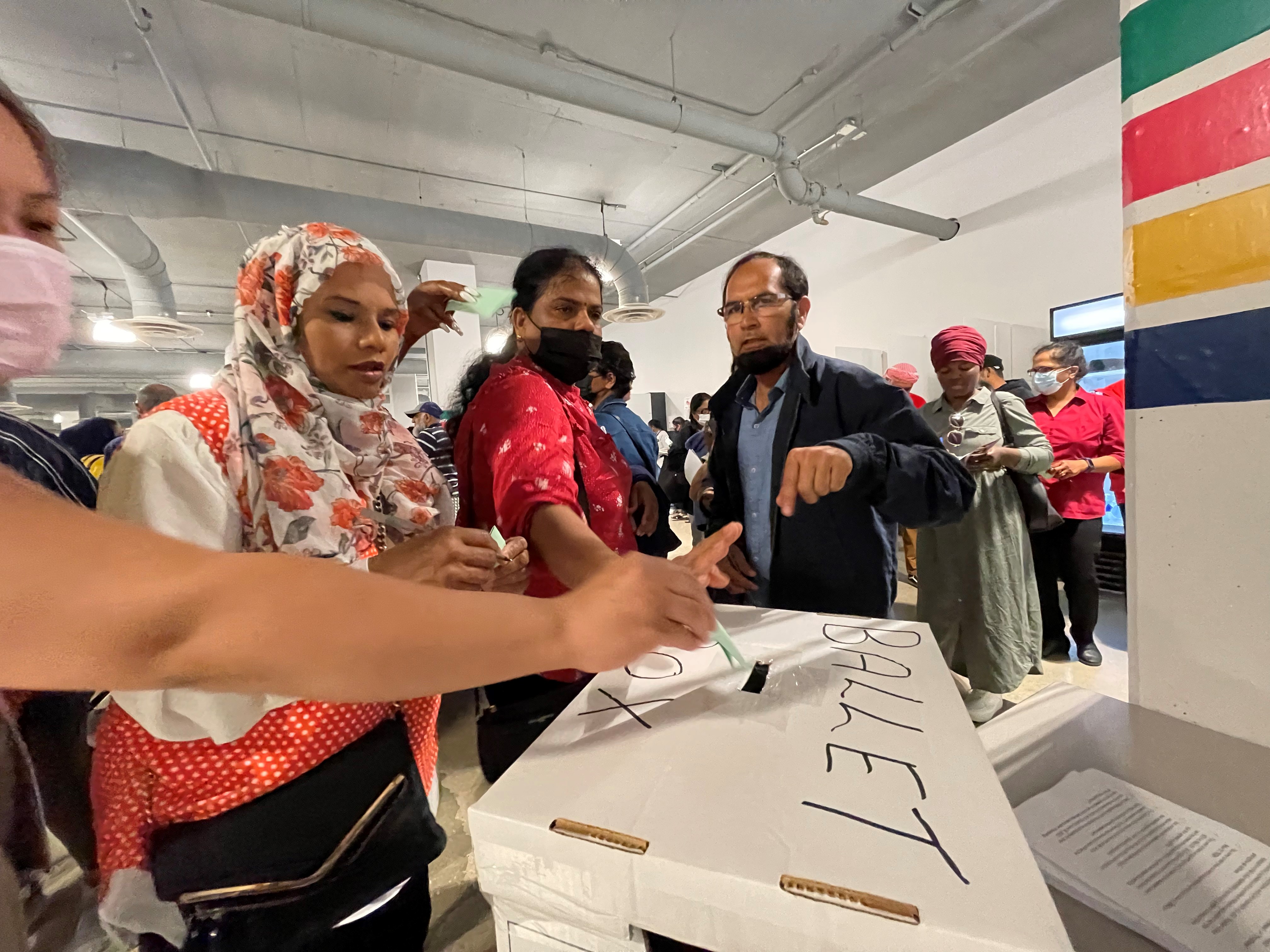 Workers line up to put their ballots in the box.