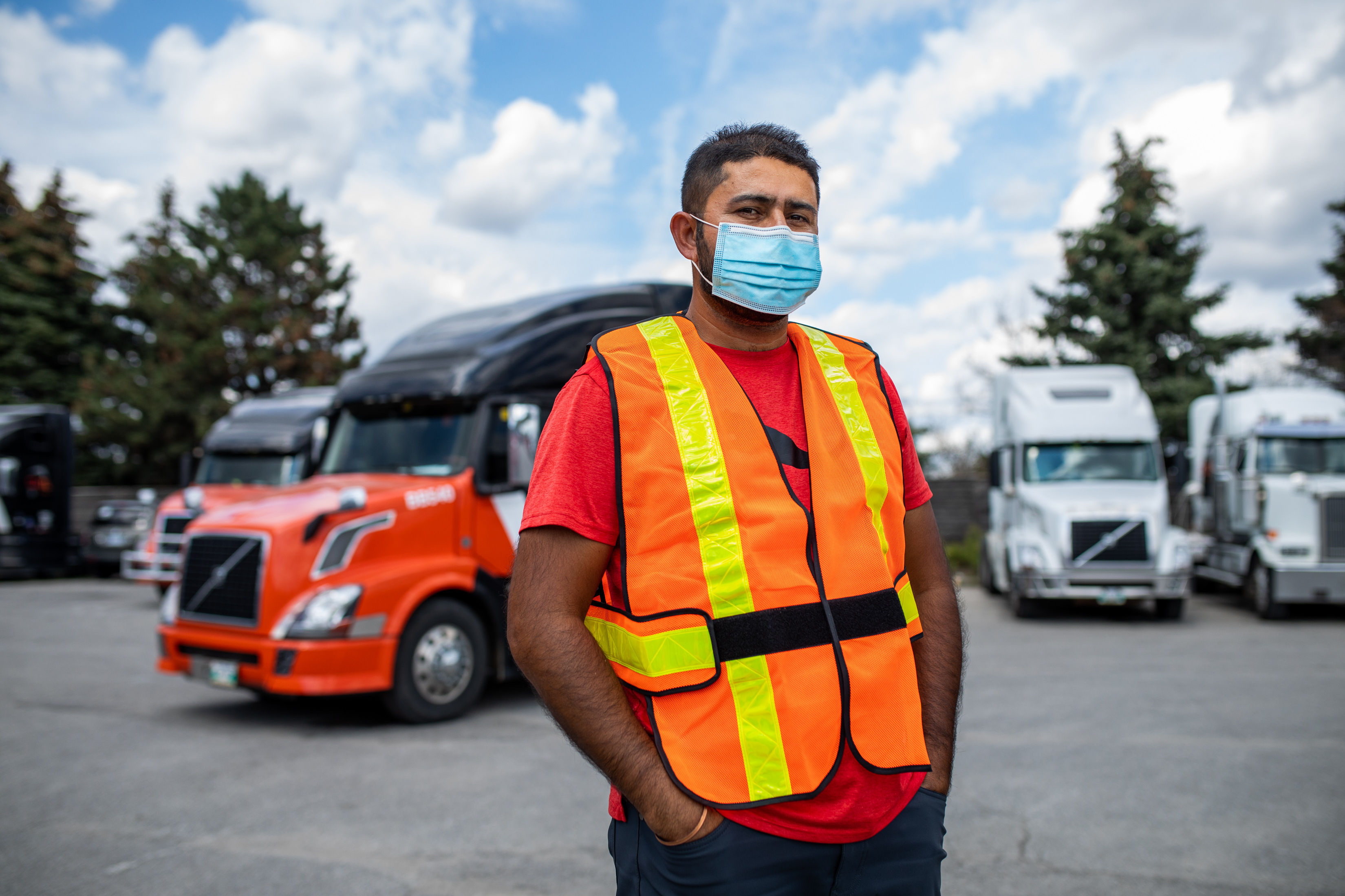 Homme en gilet de sécurité et masque facial debout devant un camion