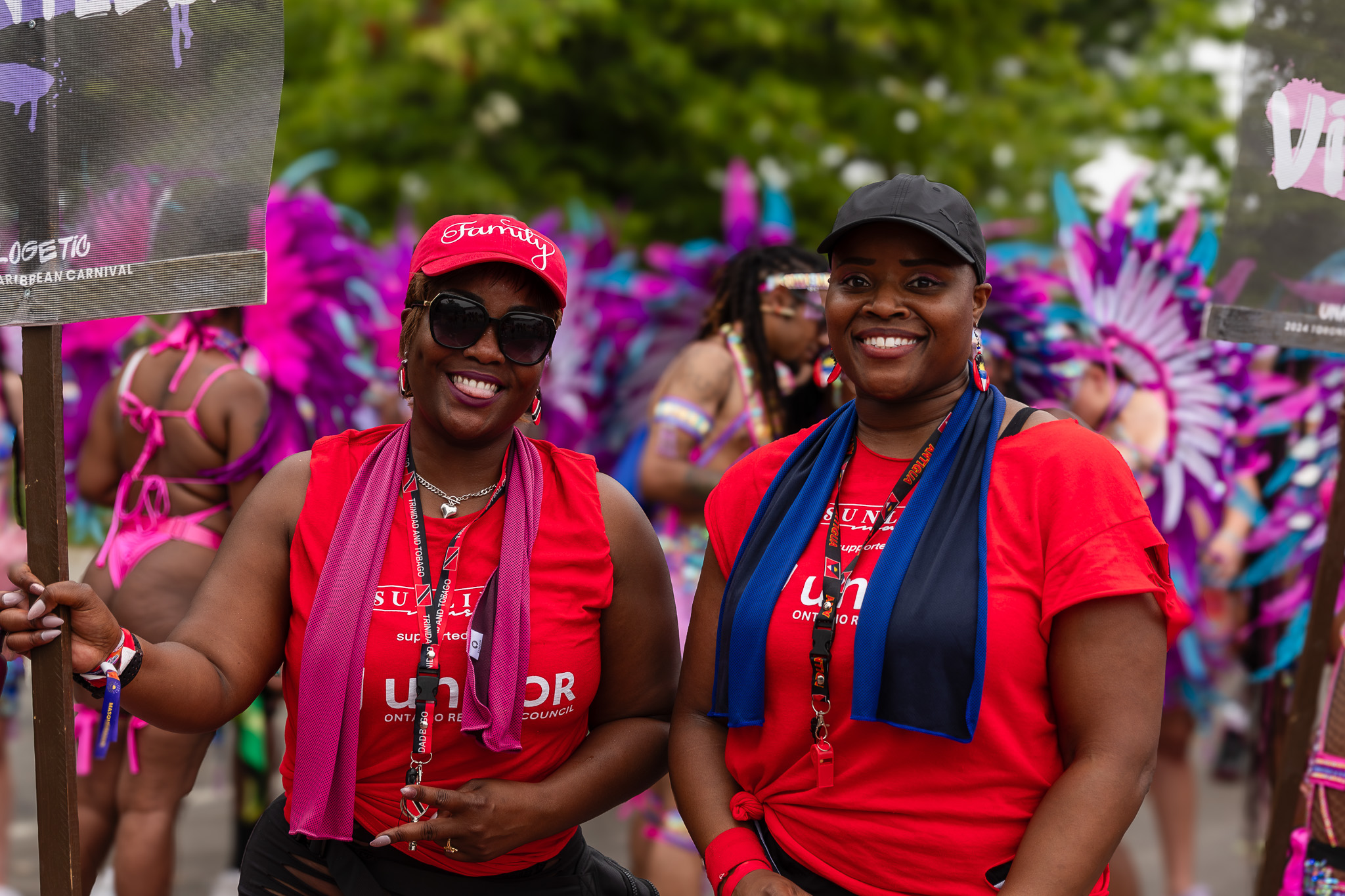 Two women in red shirts one holding a sign