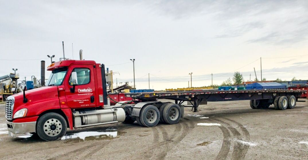 Un camion rouge avec un plateau vide garé à l’extérieur