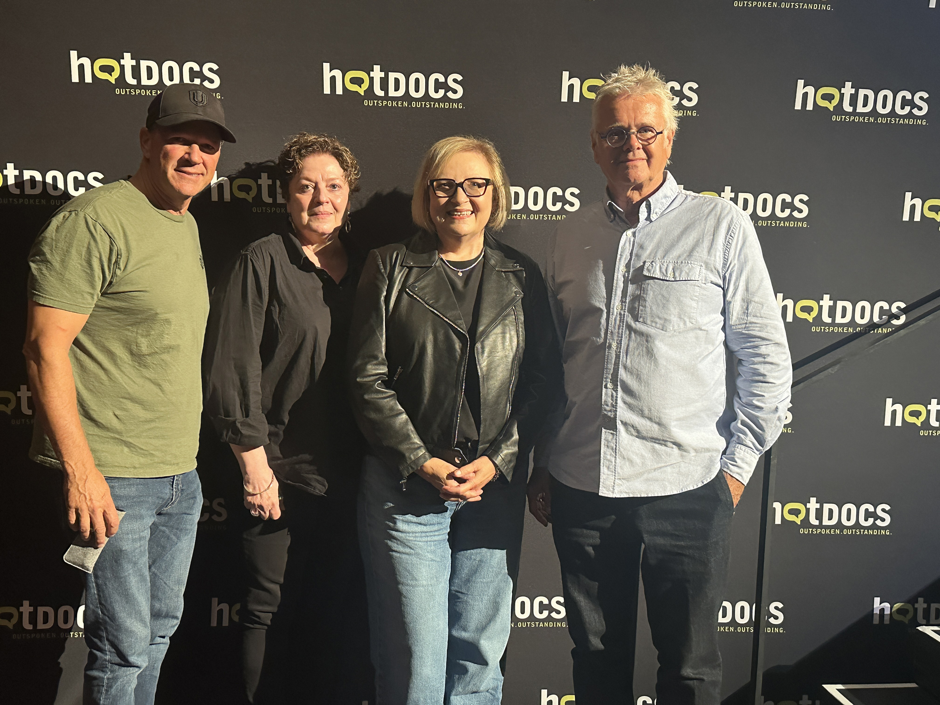 four people posing in front of a hotdocs banner