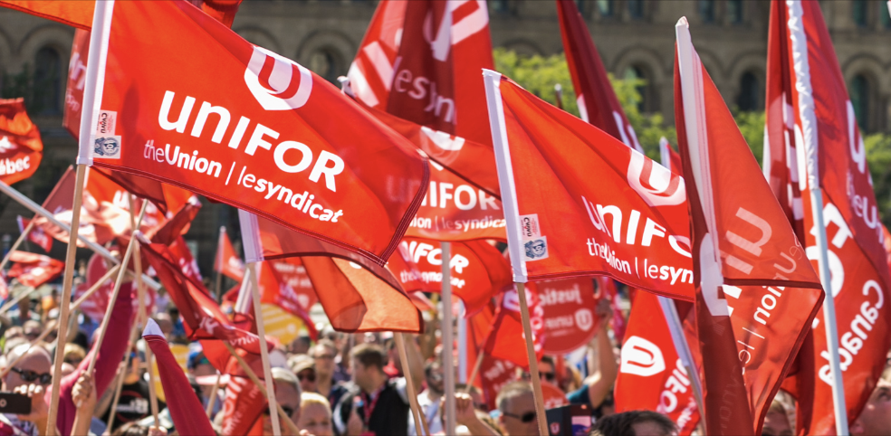 Unifor flags waving in a crowd.