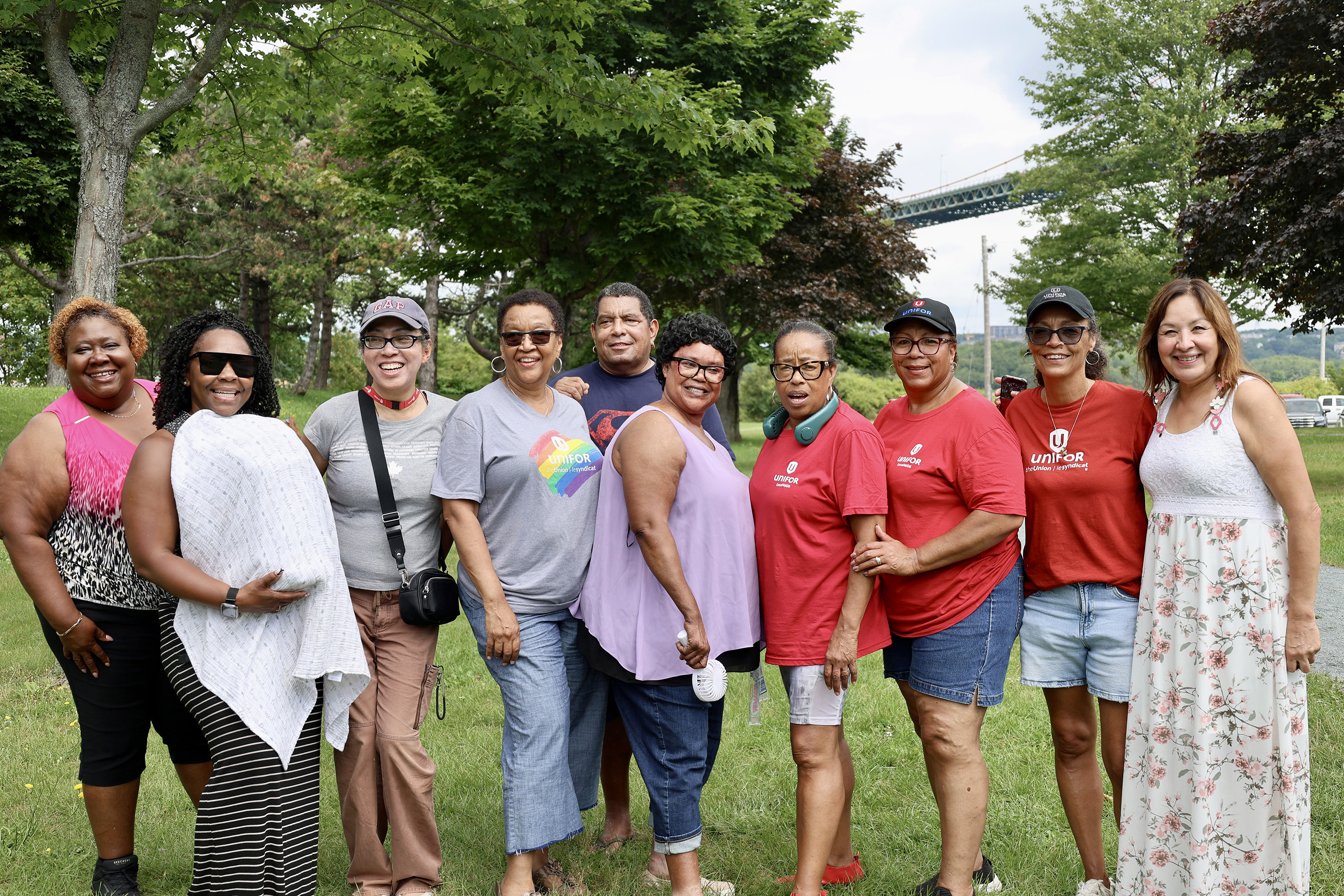 Ten people pose outside in a green park