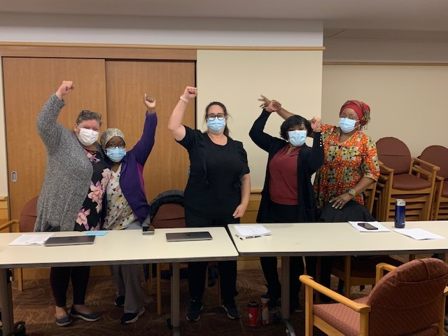 Cinq membres du comité de négociation de la section locale 8300 d'Unifor lèvent le poing en l'air après avoir négocié la première convention collective au Hillel Lodge.