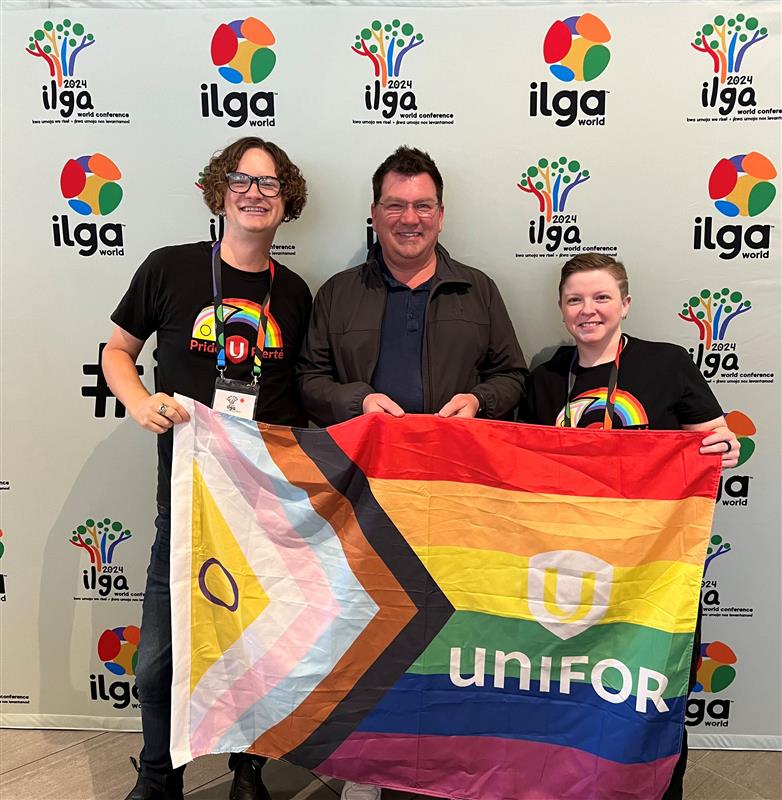 Three people holing up a trans, pride flag