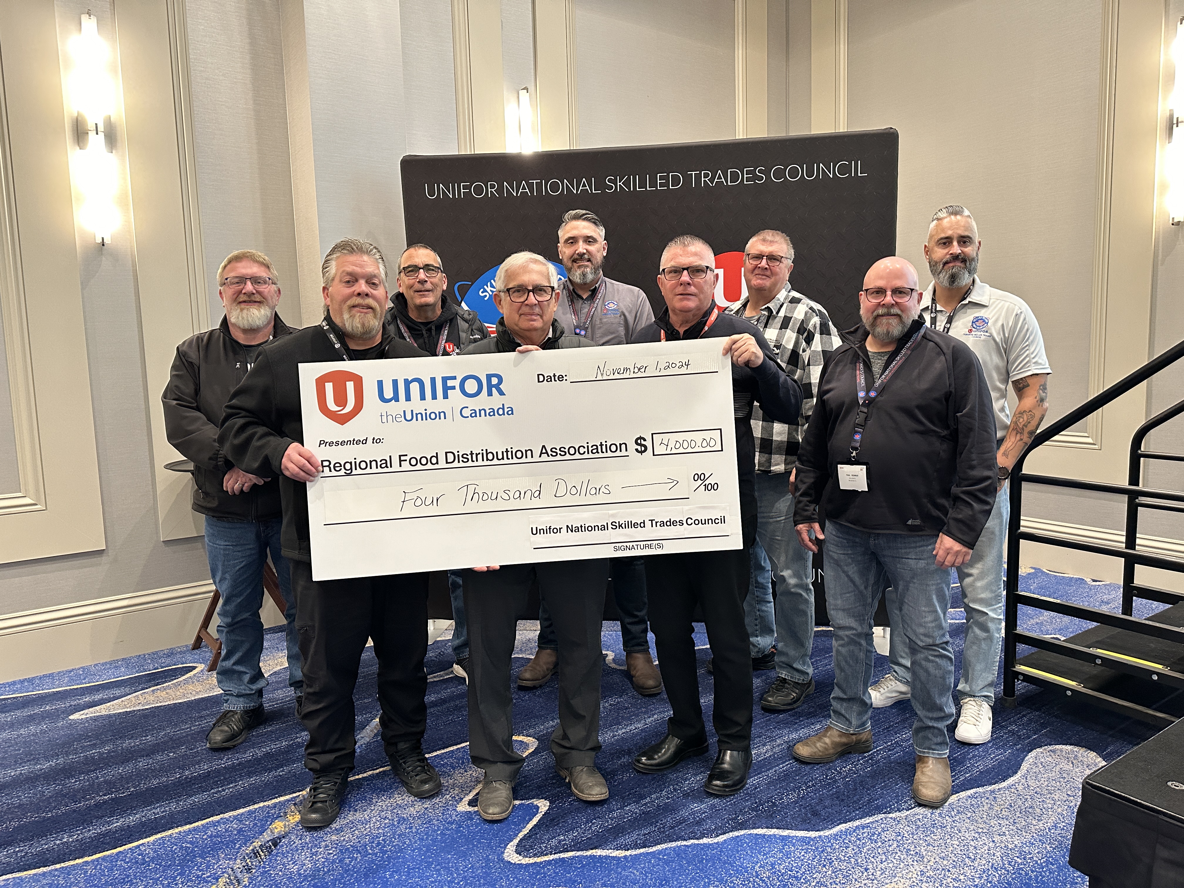 A large group posing with an oversized cheque