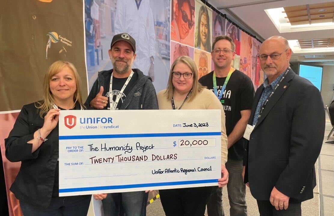 four people holding up a giant cheque