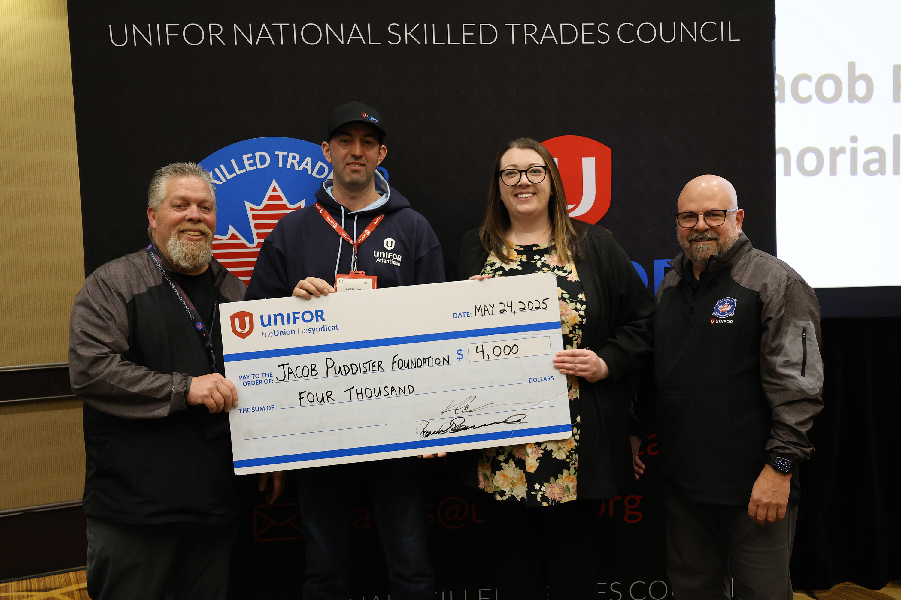 four people holding an oversized cheque