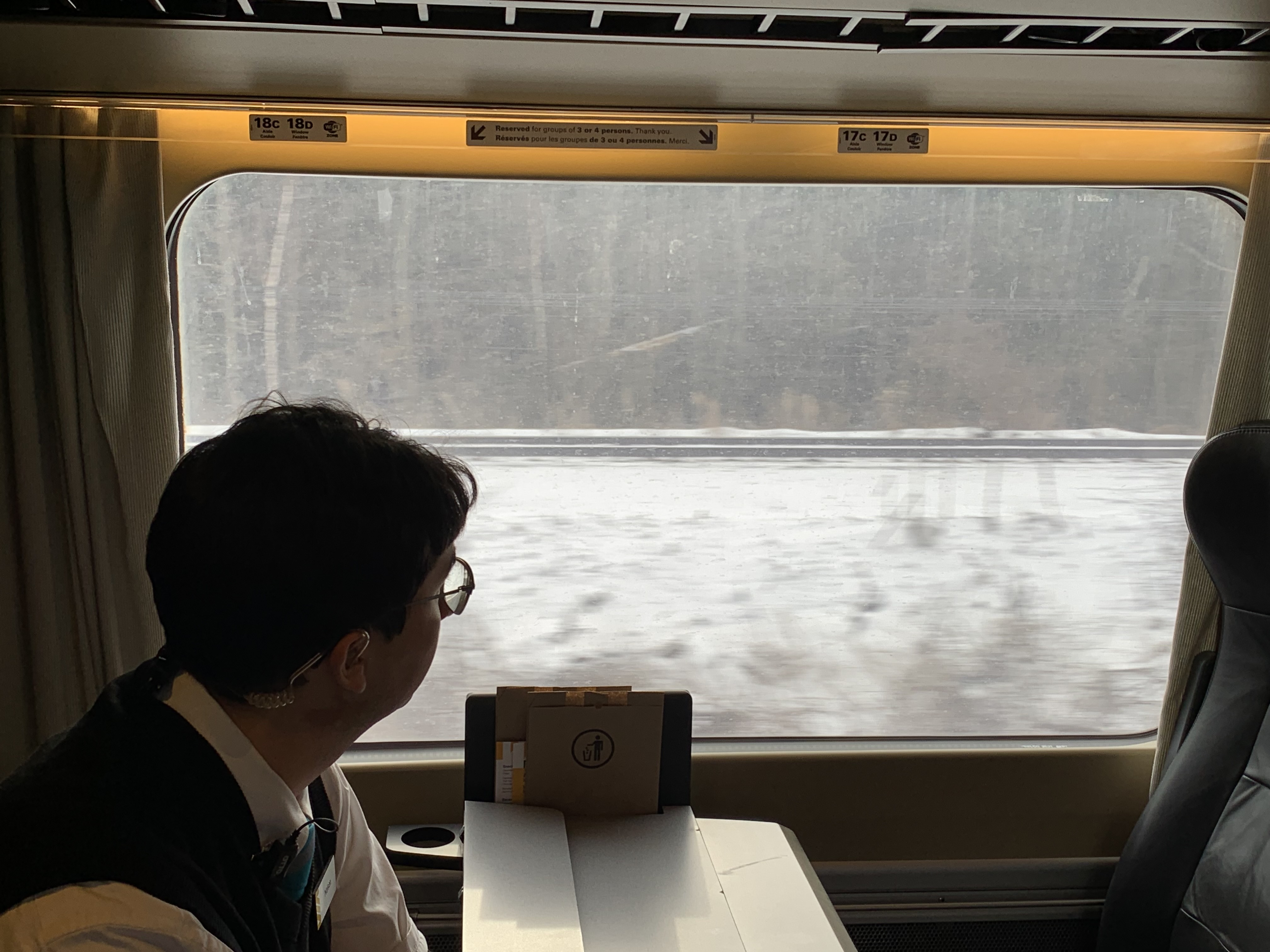 A man looks out the window of a moving train.