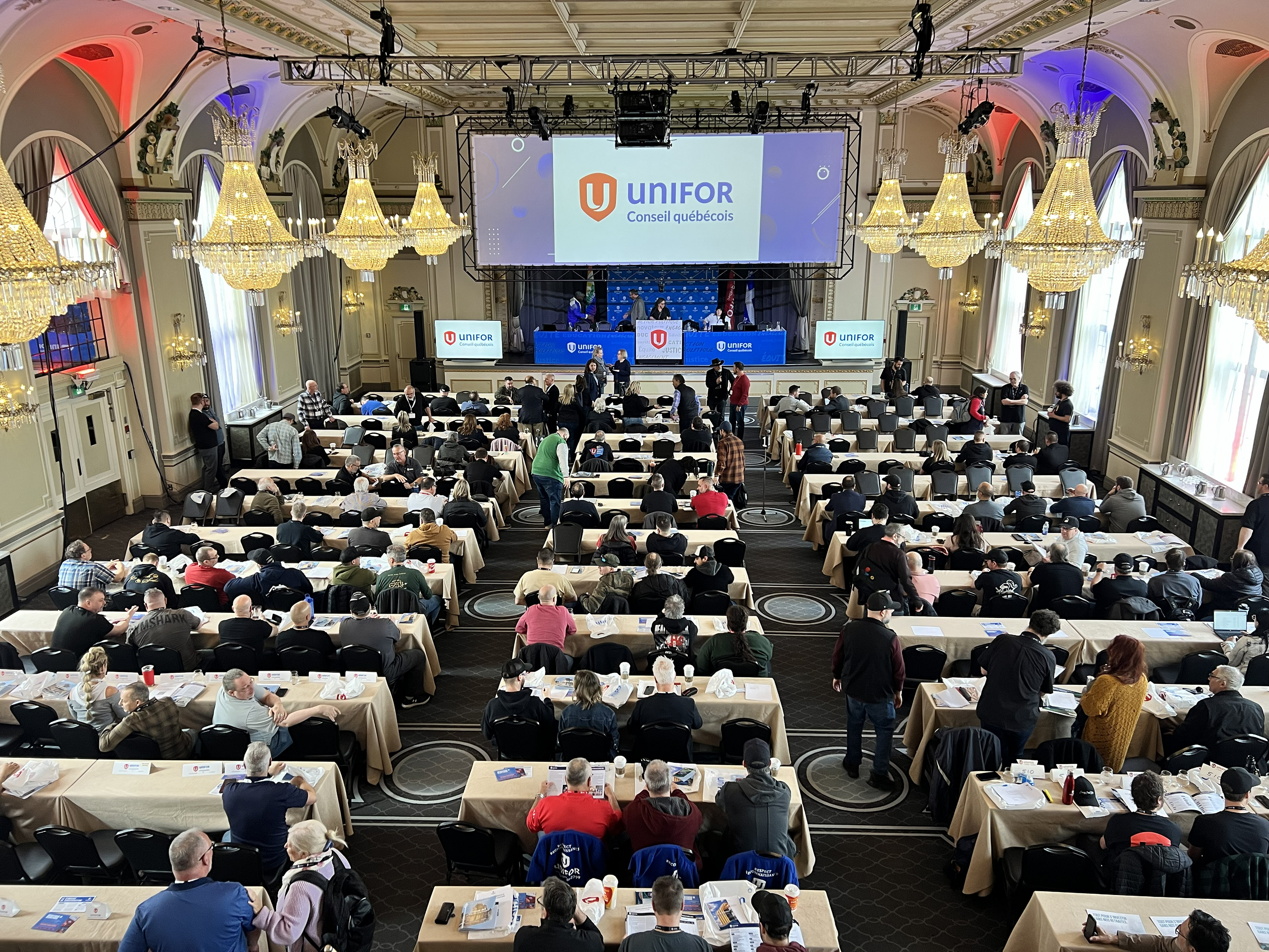 confernce from the back of a room with a Unifor logo on a large screen at the back