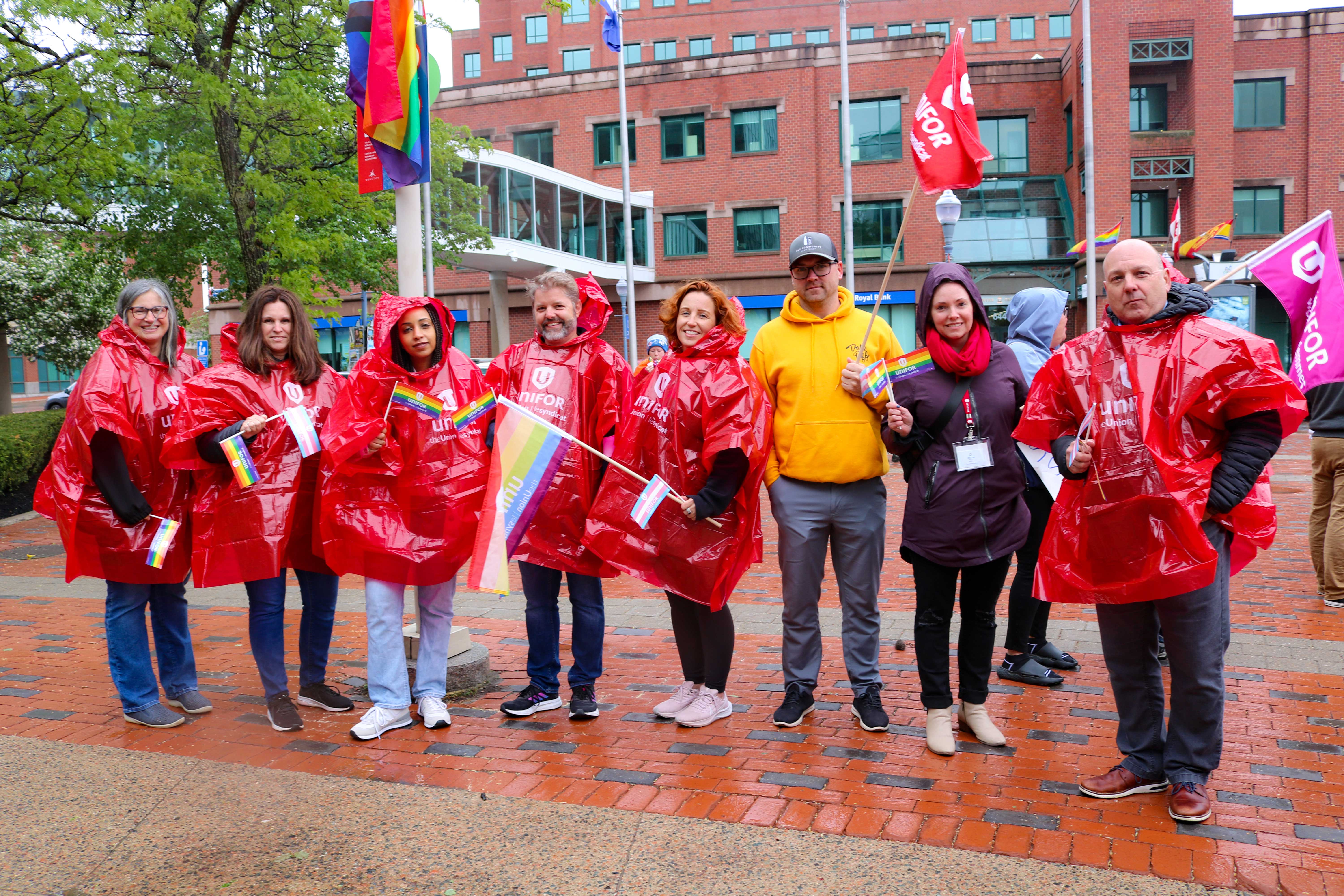 members standing in rain coats with Unifor flags and pride flags.
