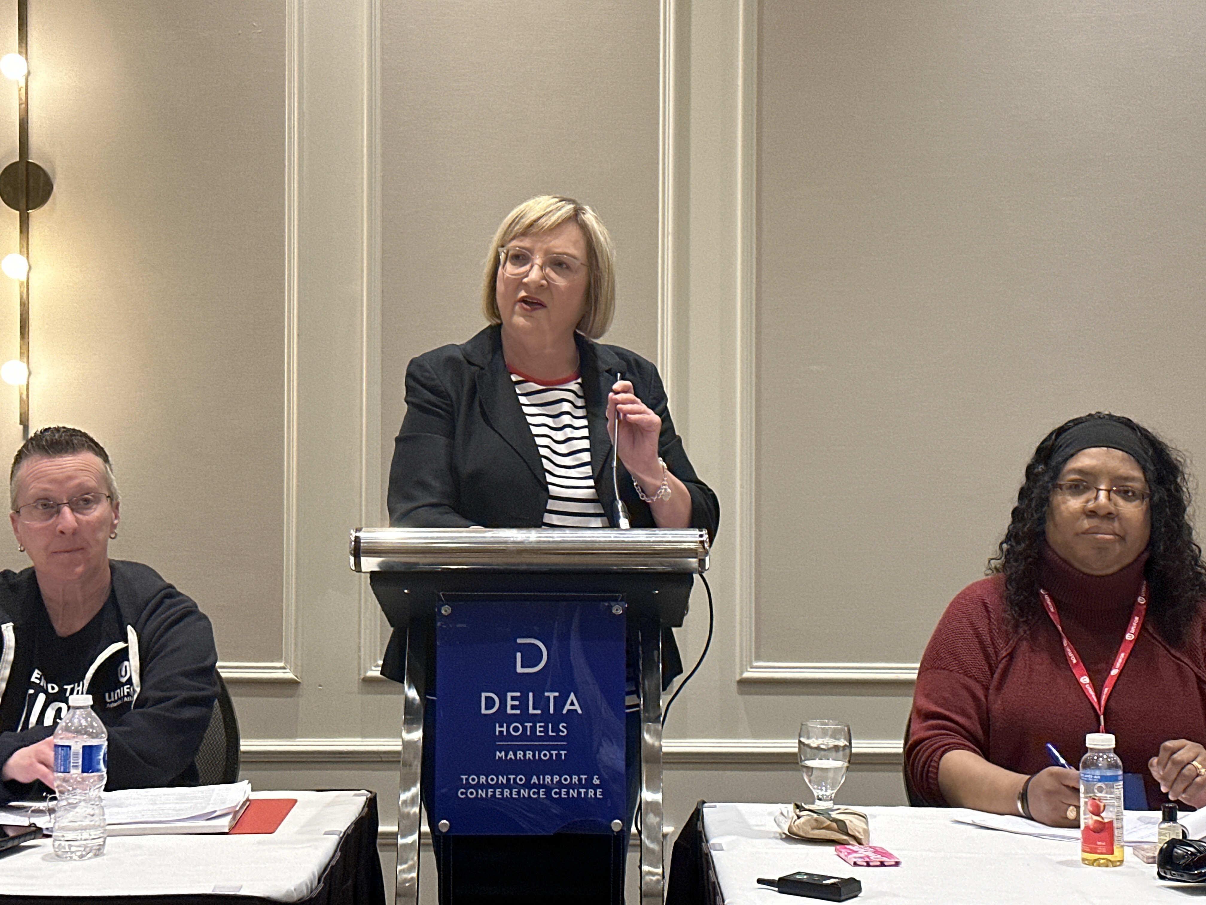 A women stands and speaks at a podium