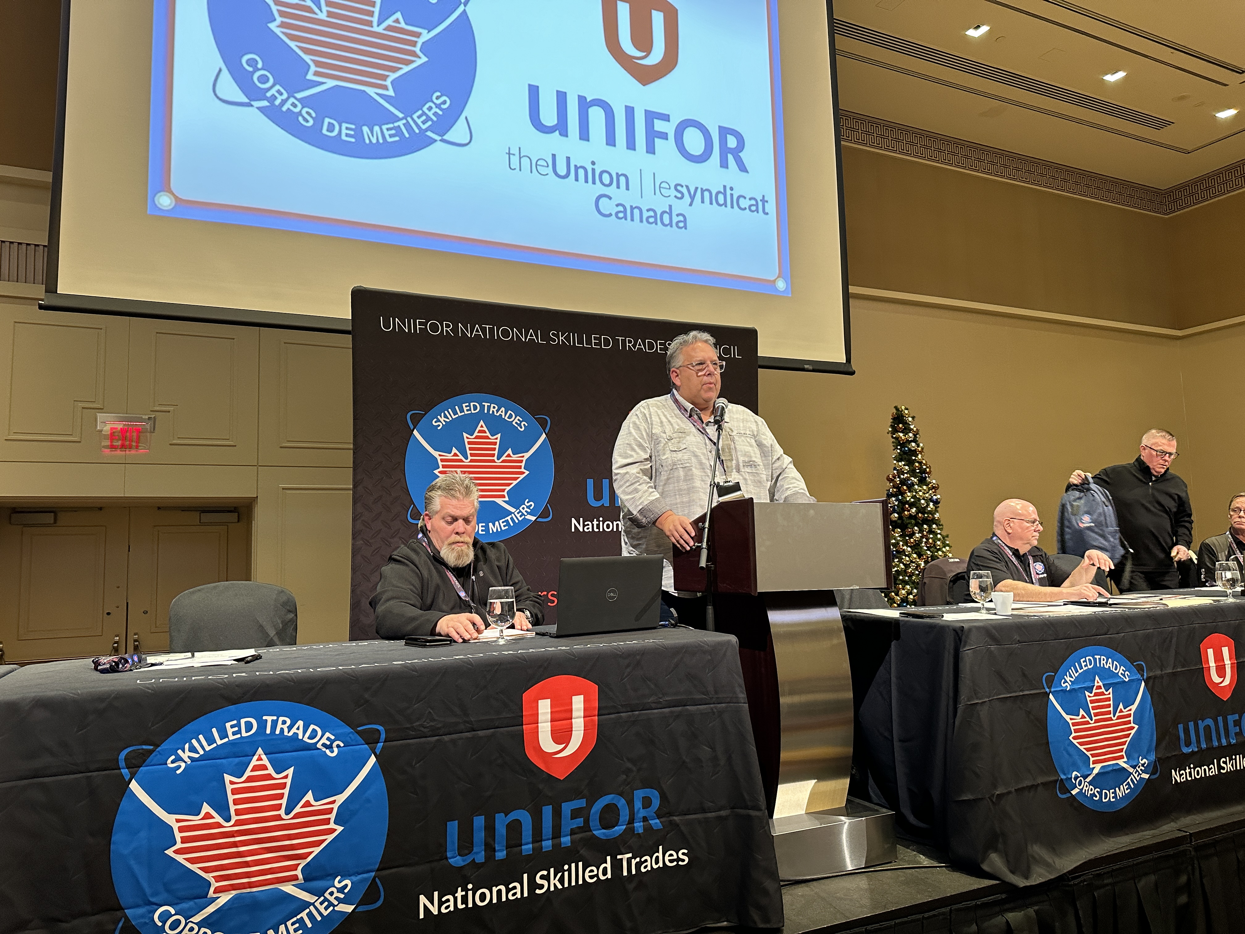 A man speaks at a podium a man sits at each side