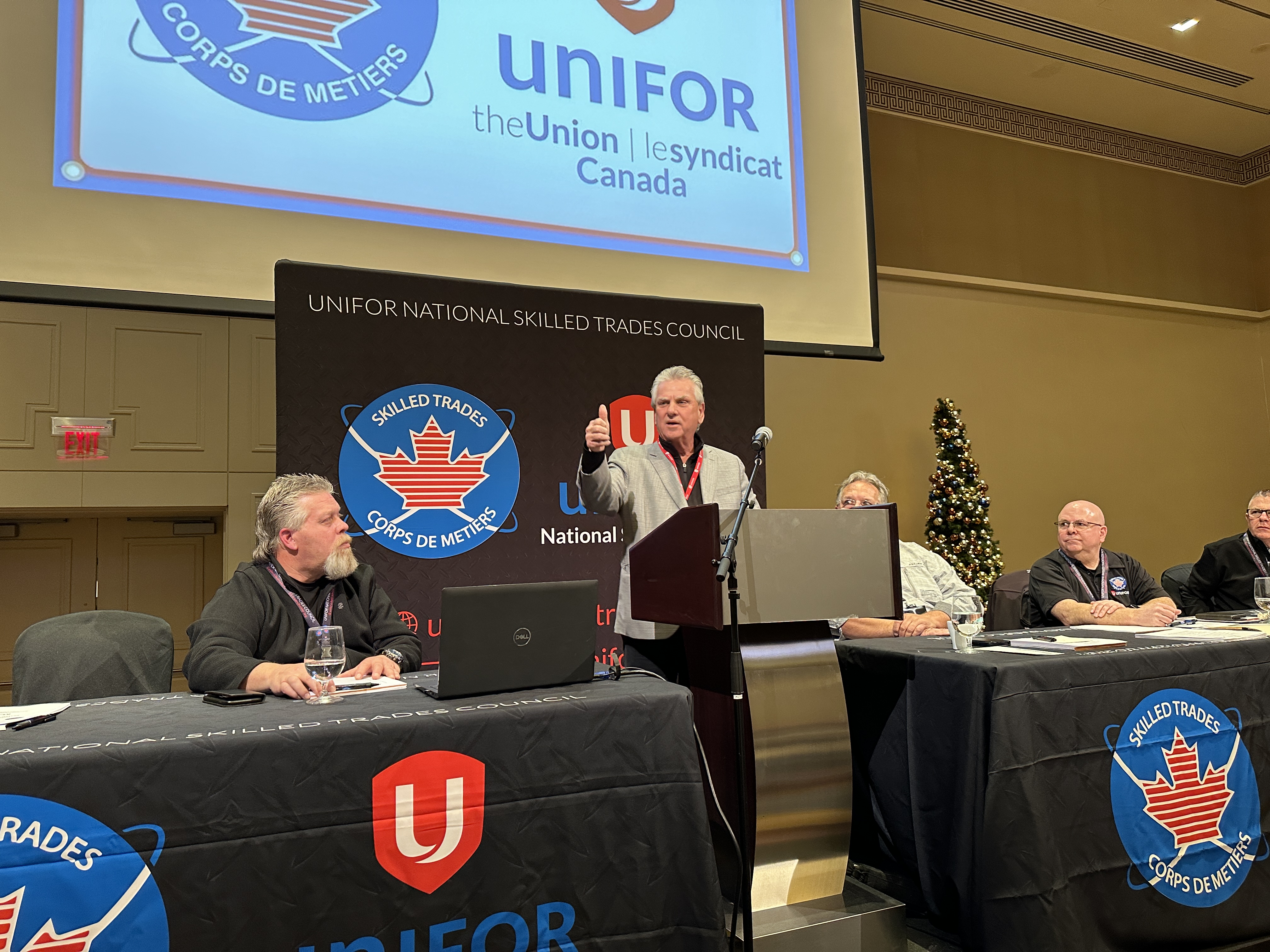 A man speaking at a podium with a man seated at each side
