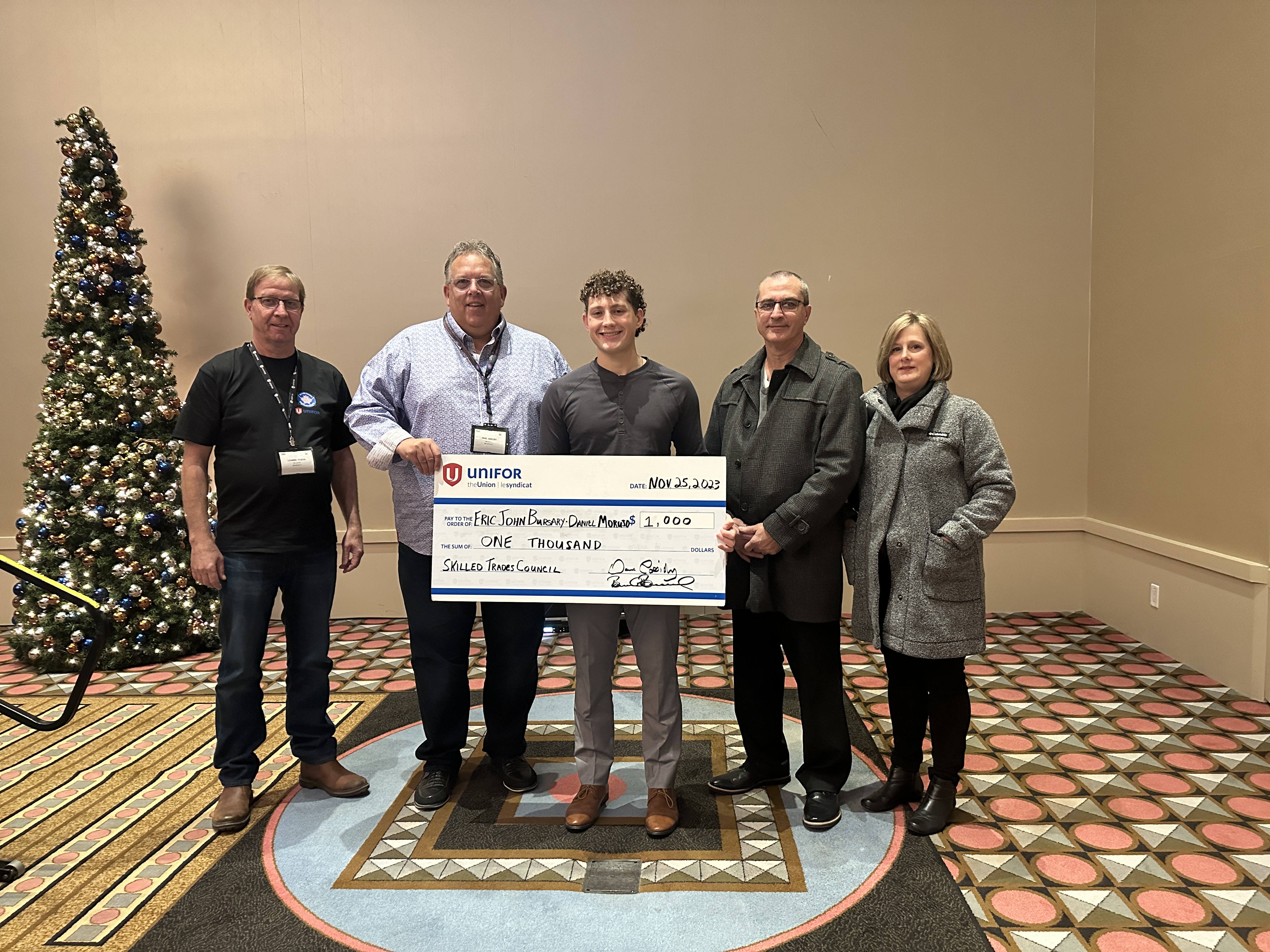 five people hold up a over sized cheque