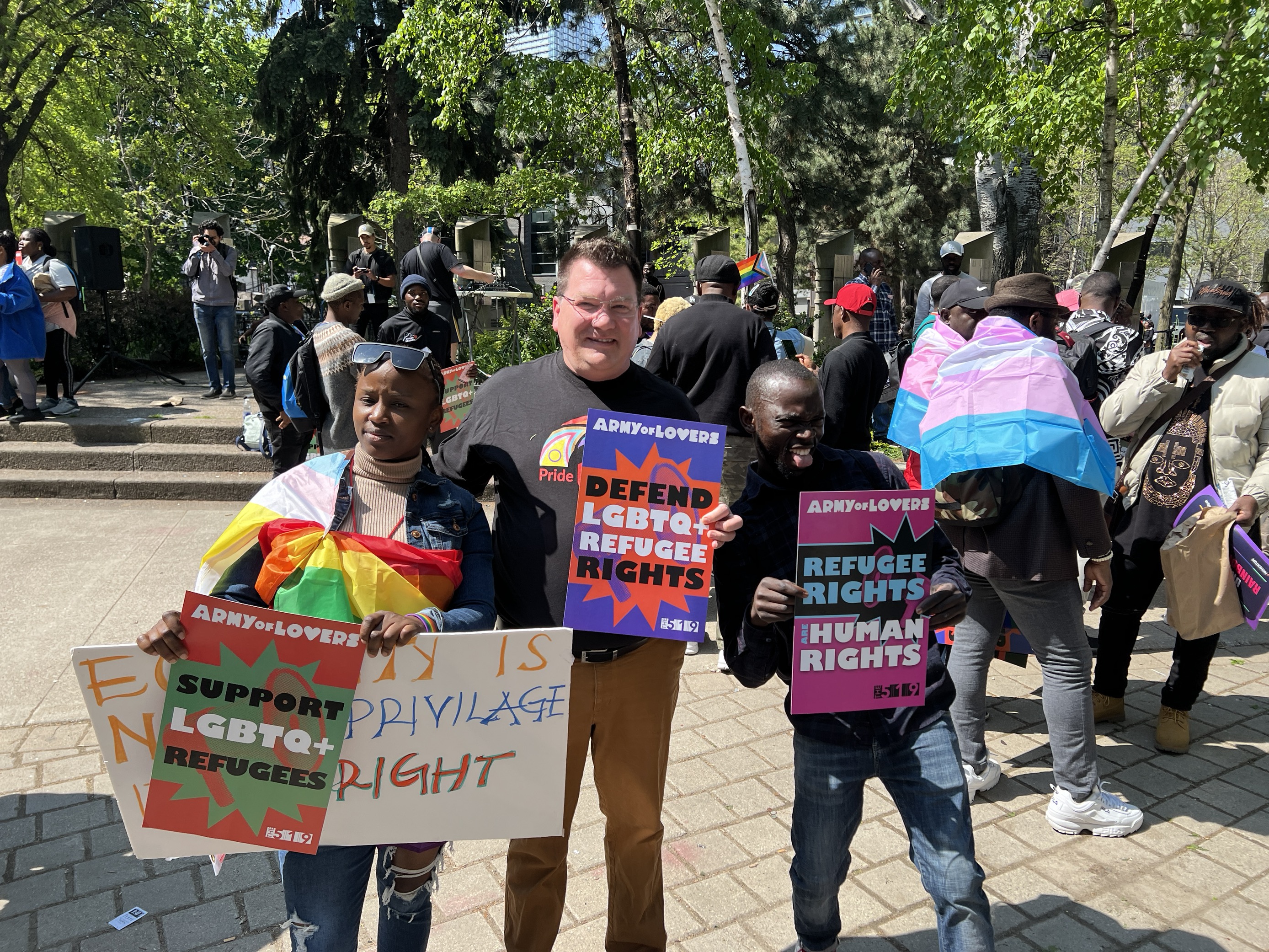 Three people standing outside holding up place cards