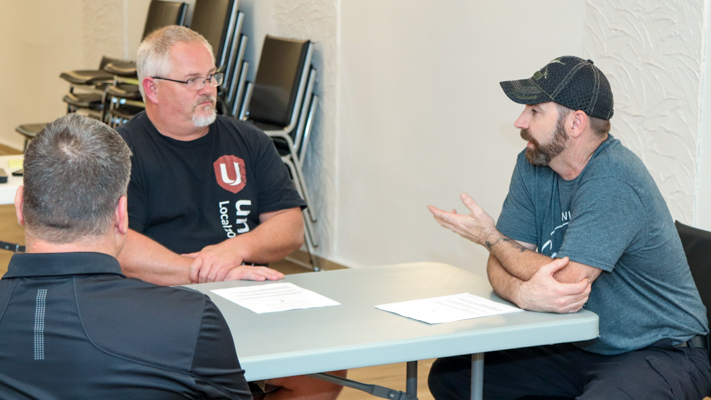 Three people seated at a table talking.