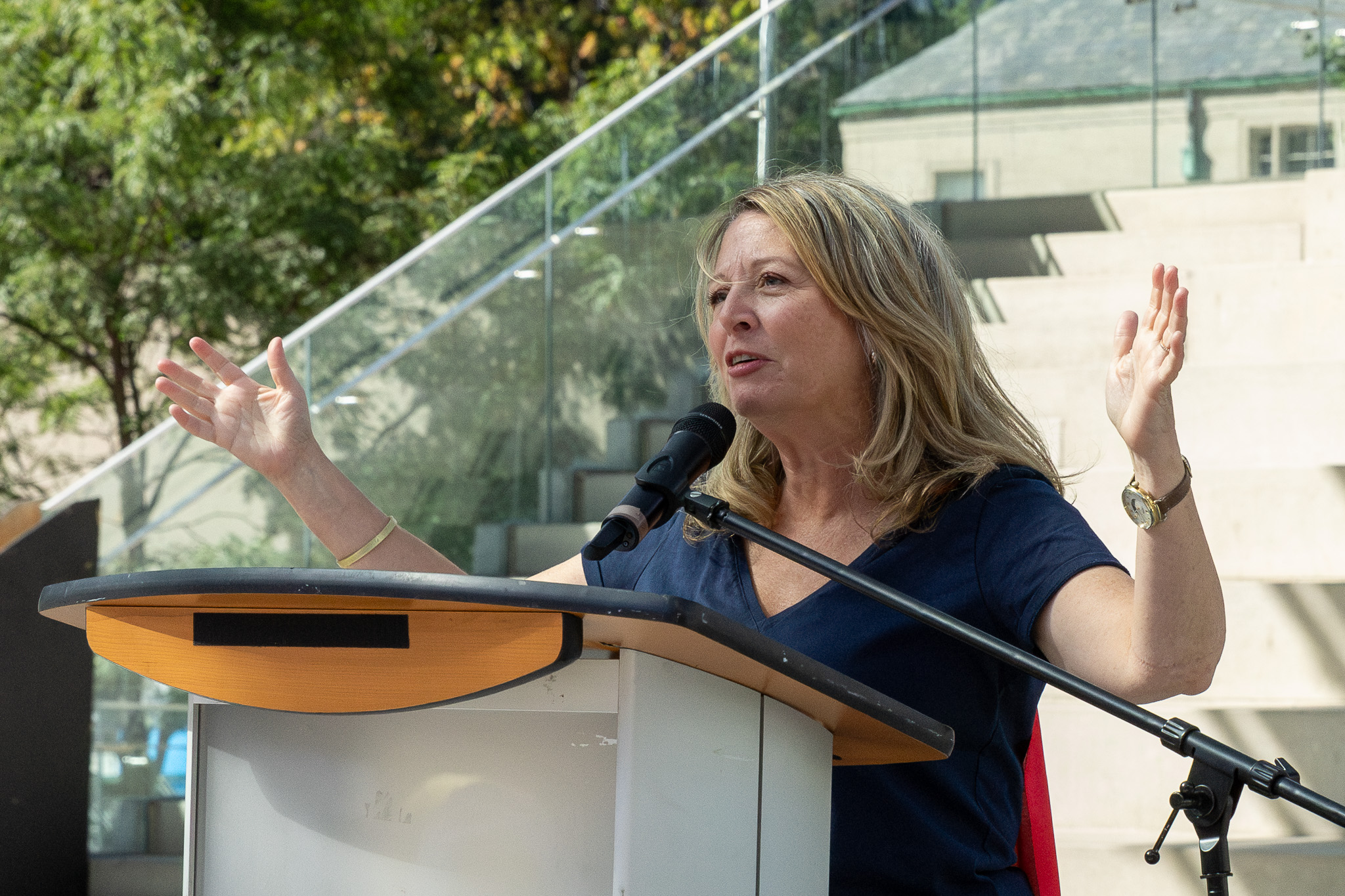 A woman with arms raised in front of a microphone