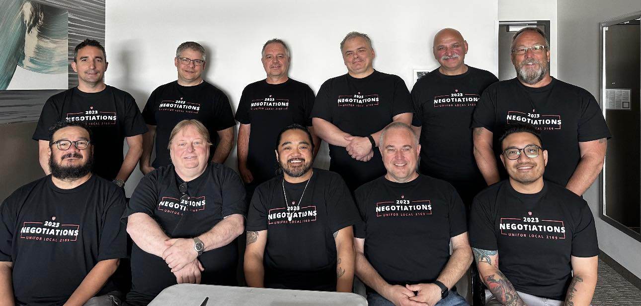 Unifor Local 2169 bargaining committee members seated in two rows wearing matching shirts with text that reads 2023 negotiations.