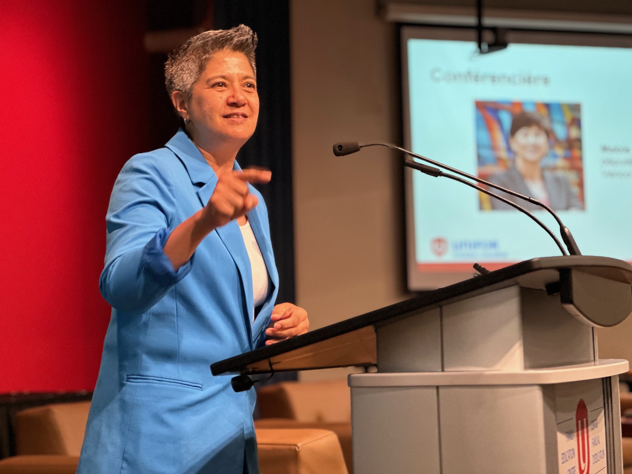 A person speaks at a podium finger pointing out