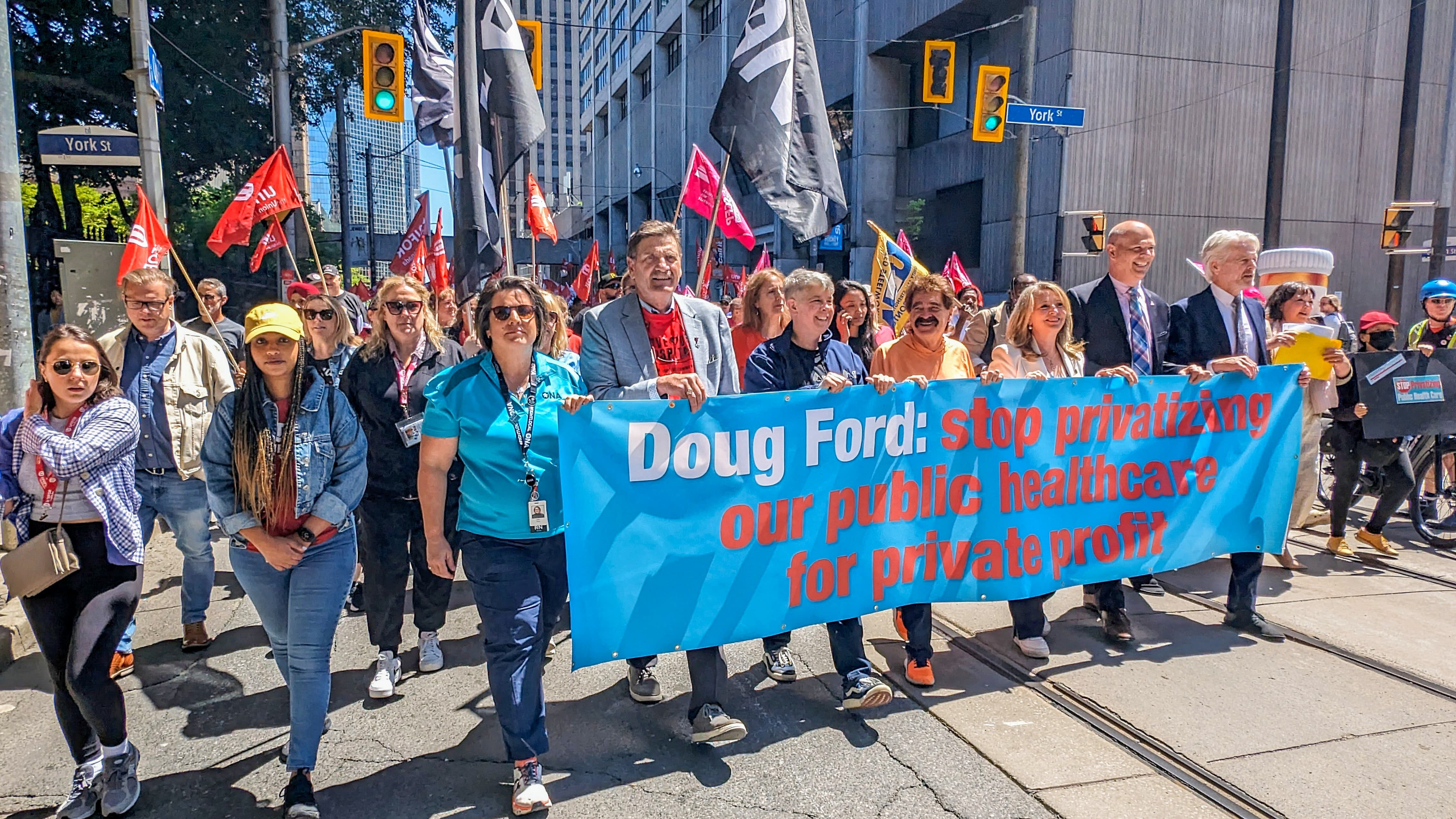 the front of a labour march with the front row of people caring a large banner
