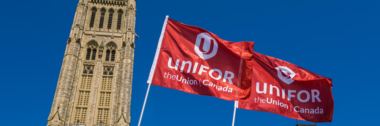Two Unifor flags fly in front of the Peace Tower on Parliament Hill in Ottawa.