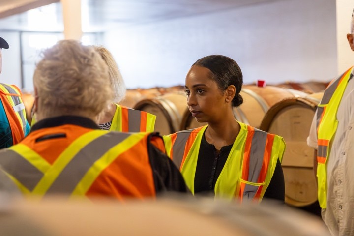 Close up of a women wearing a safety vest in a room full of wine barrels