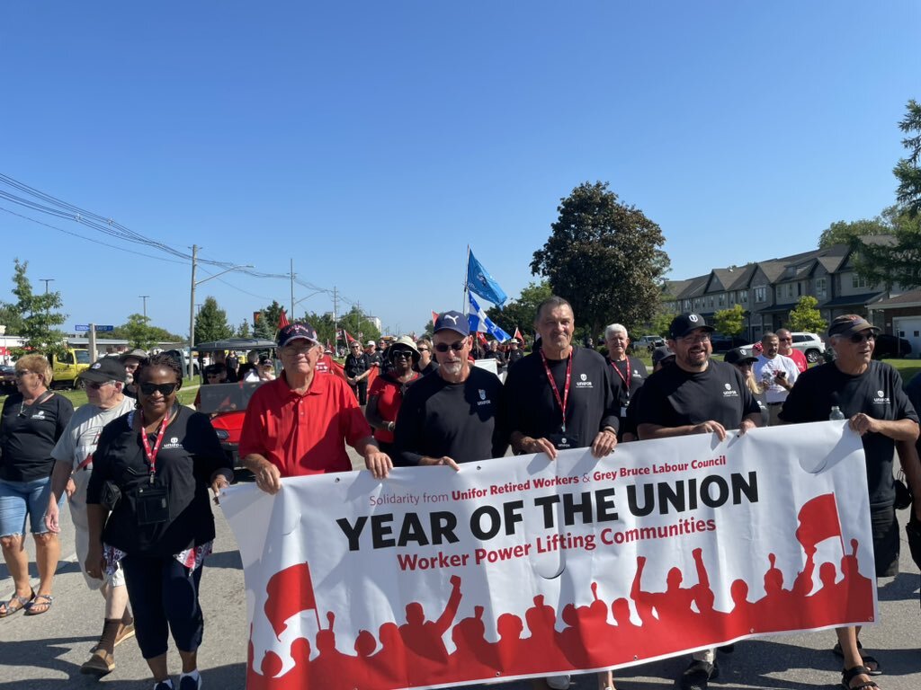 Retired workers' marching in the Port Elgin Labour Day parade holding a banner.