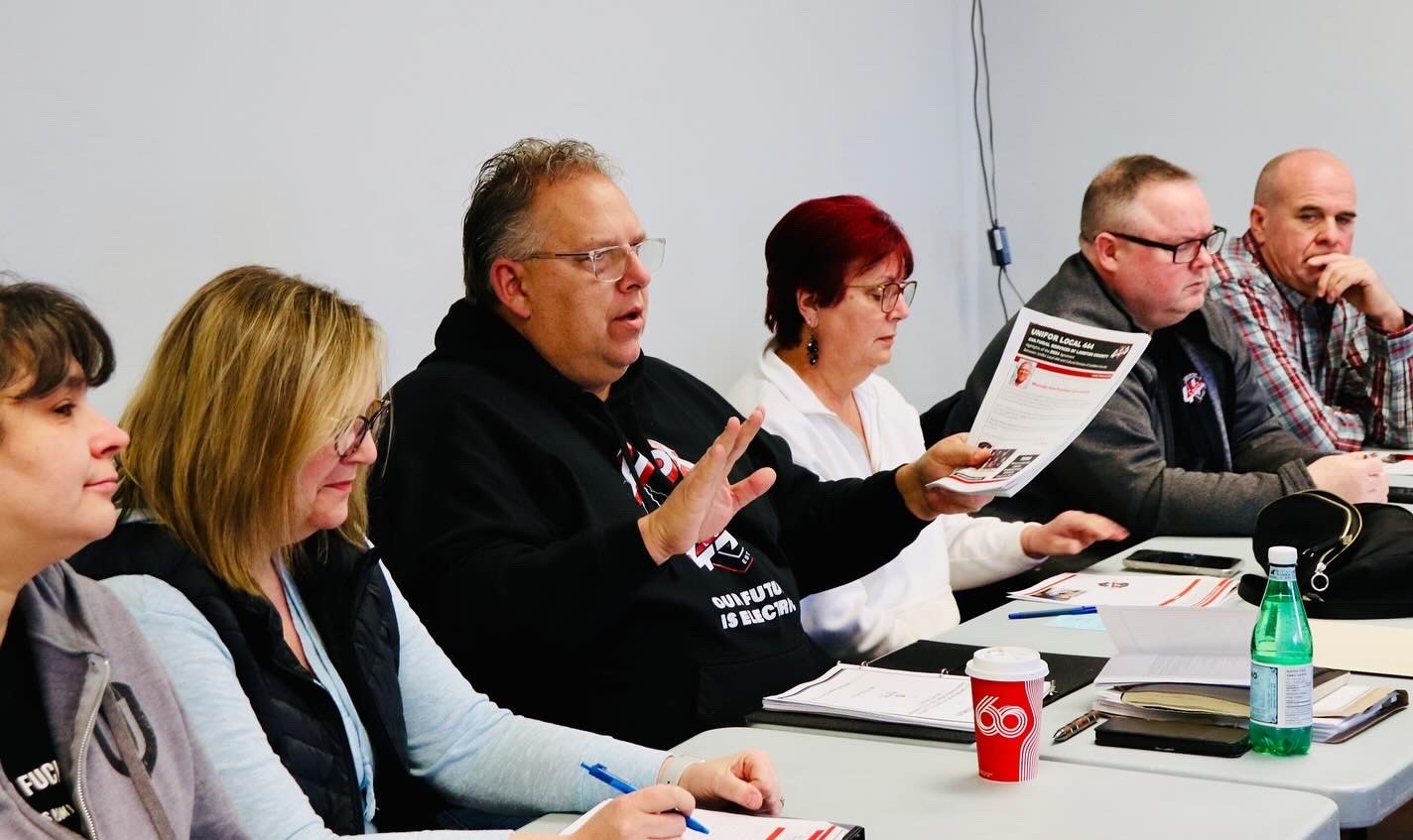 six people sitting at a long table talking