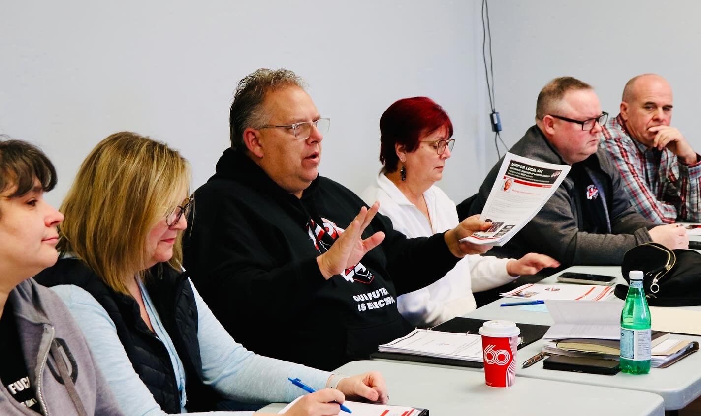 six people sitting at a long table talking 