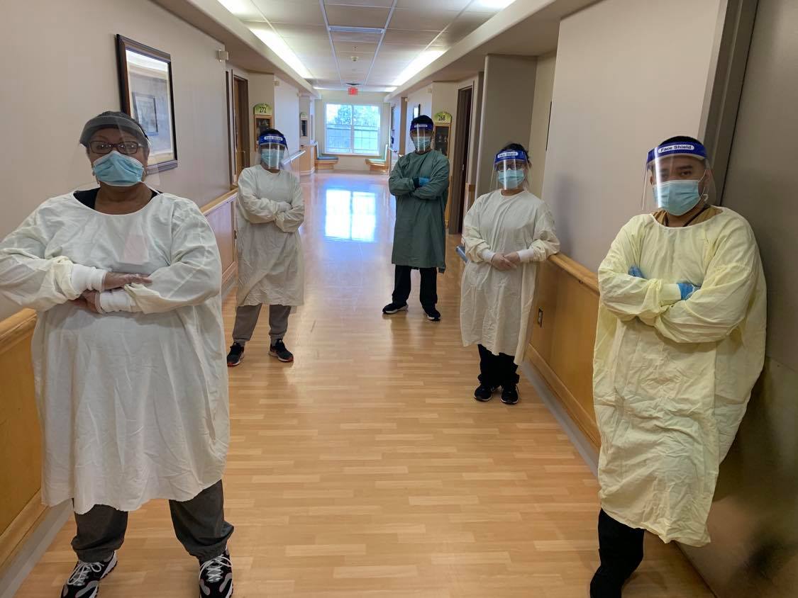 workers in personal protective equipemnt standing in a hallway socially distant