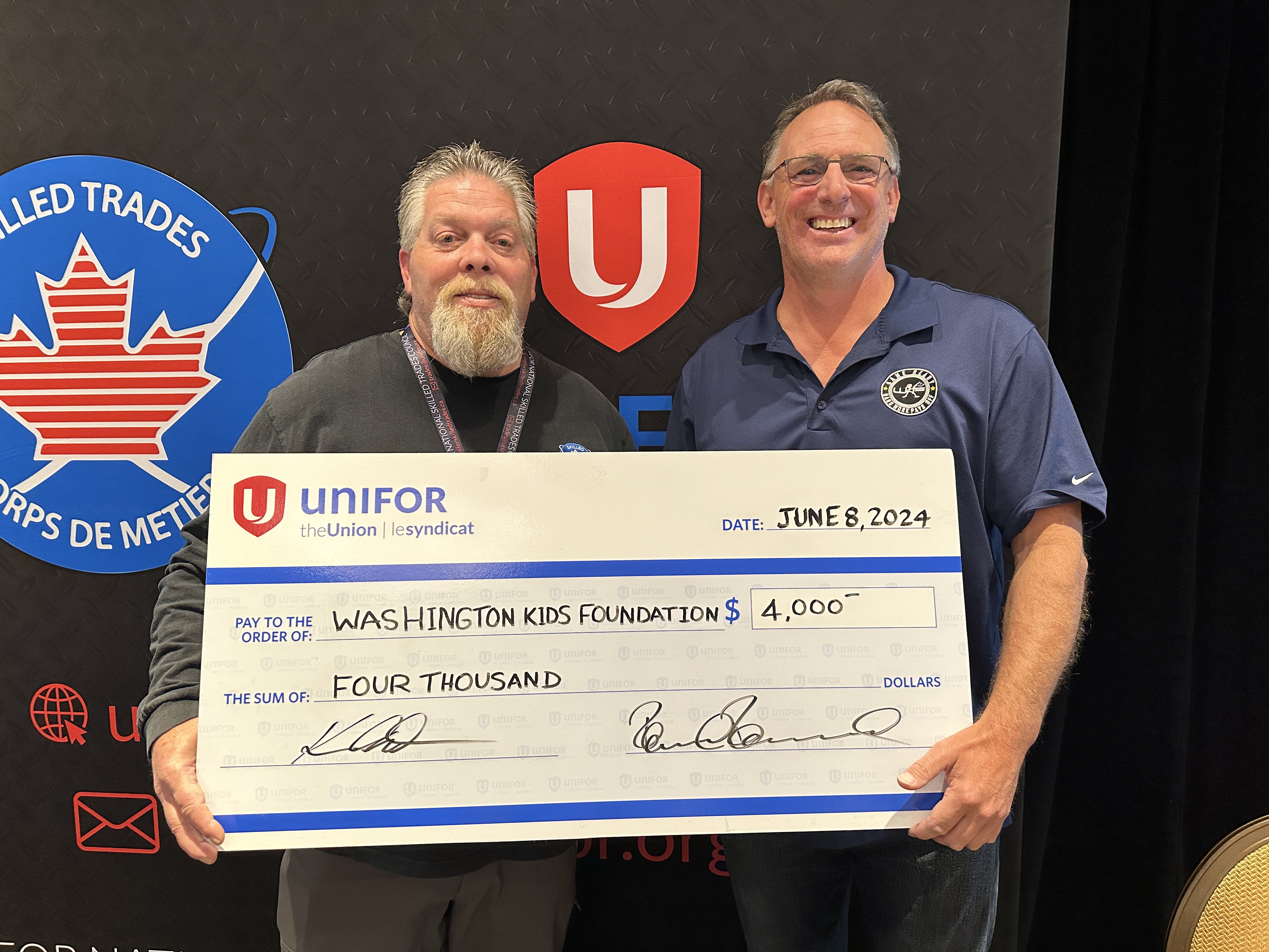 Two men hold up a large oversized cheque