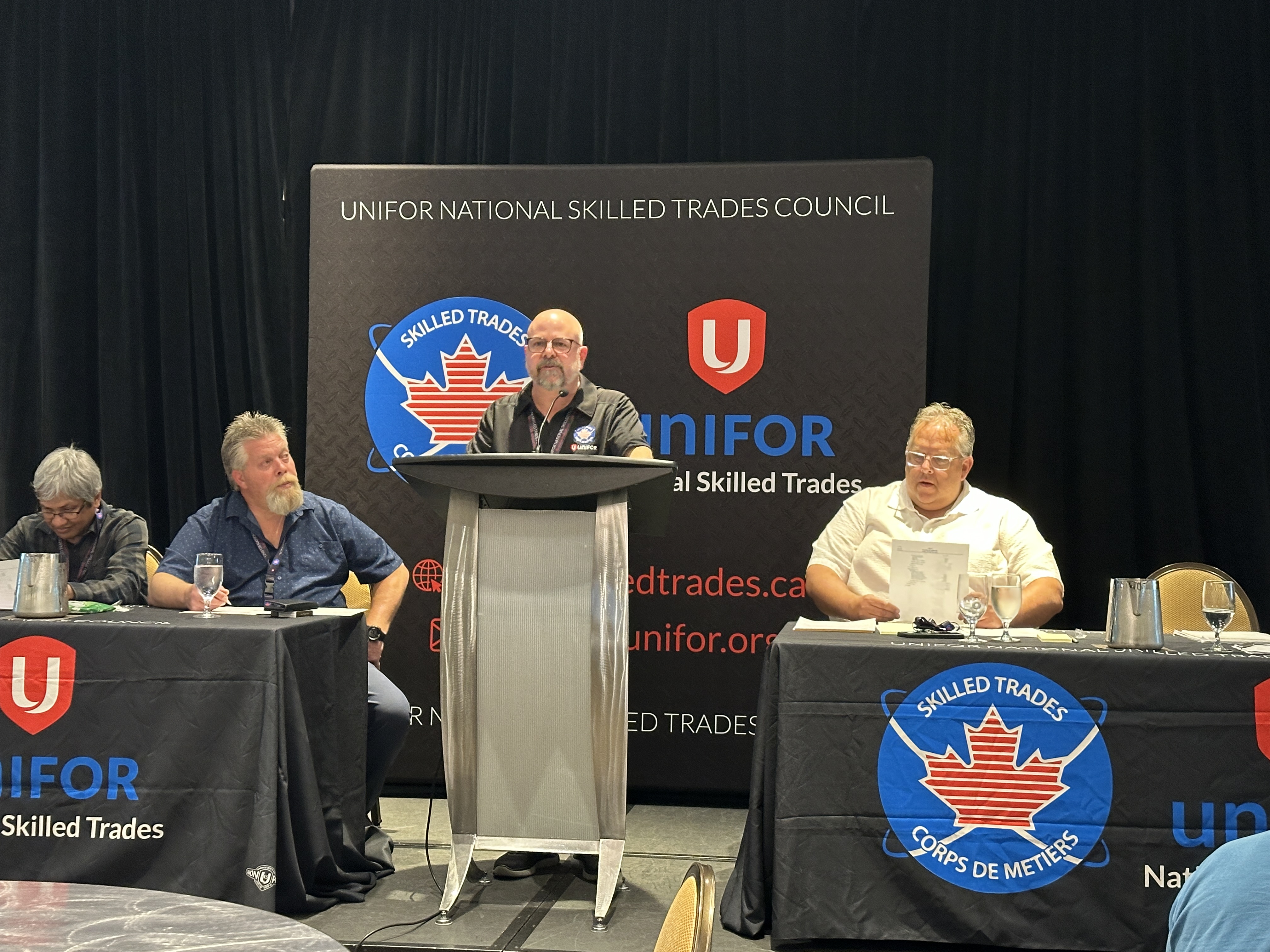 Man stands at a podium in front of a presentation screen