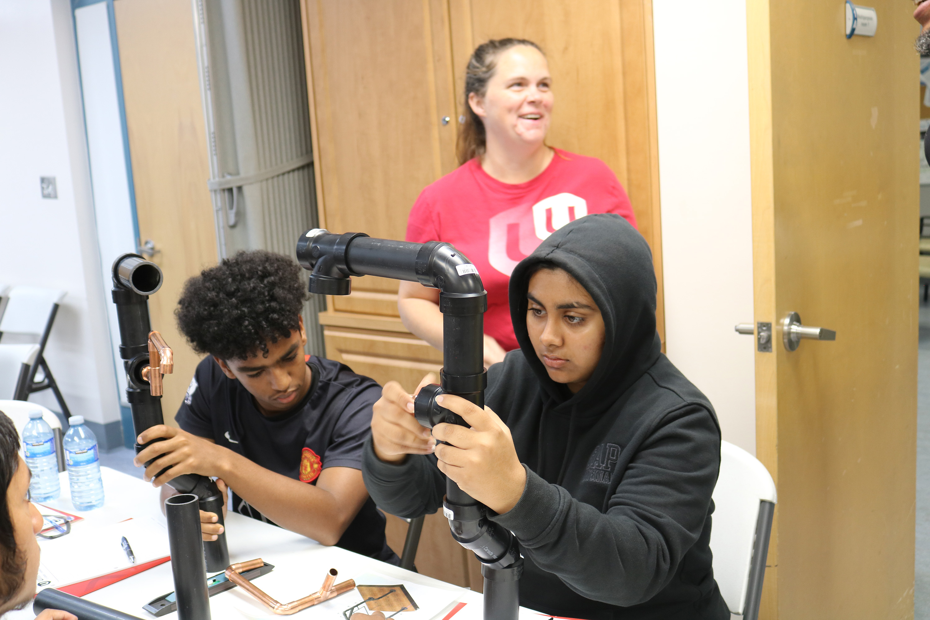 students working hands on a teacher in the background