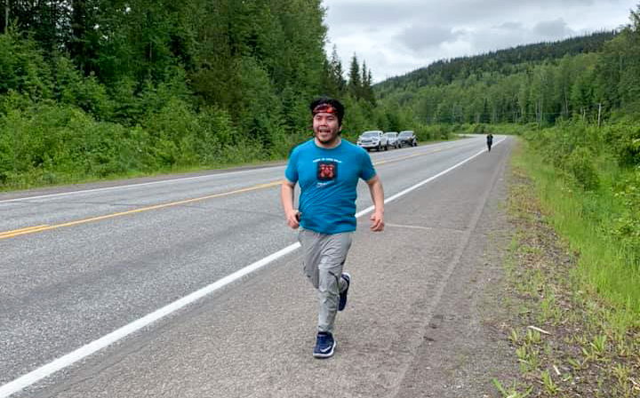 Young man running at the side of a rural highway.