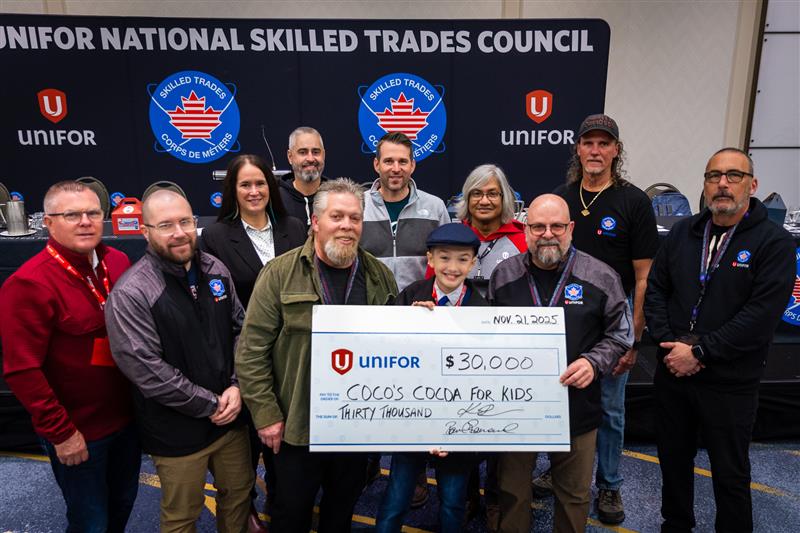 A large group standing behind a oversized cheque